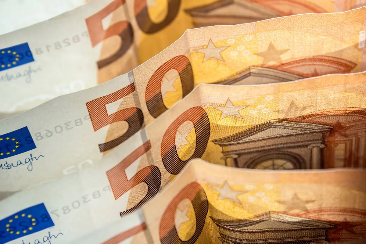 Close up of several fifty euro banknotes fanned out in a row, showing the large orange 50 numerals and the European stars